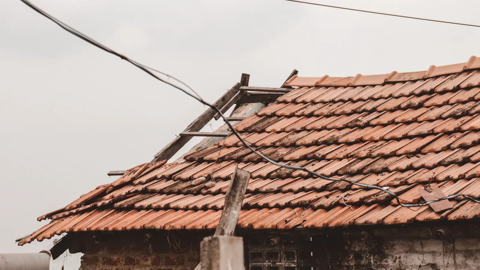 An old rural house with a damaged clay tile roof in Chennai, India, showing signs of decay.