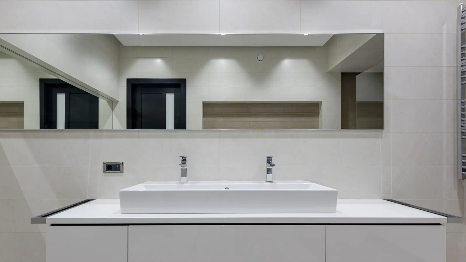 Stylish bathroom with mirror over white table with double vessel sink and towel warmer