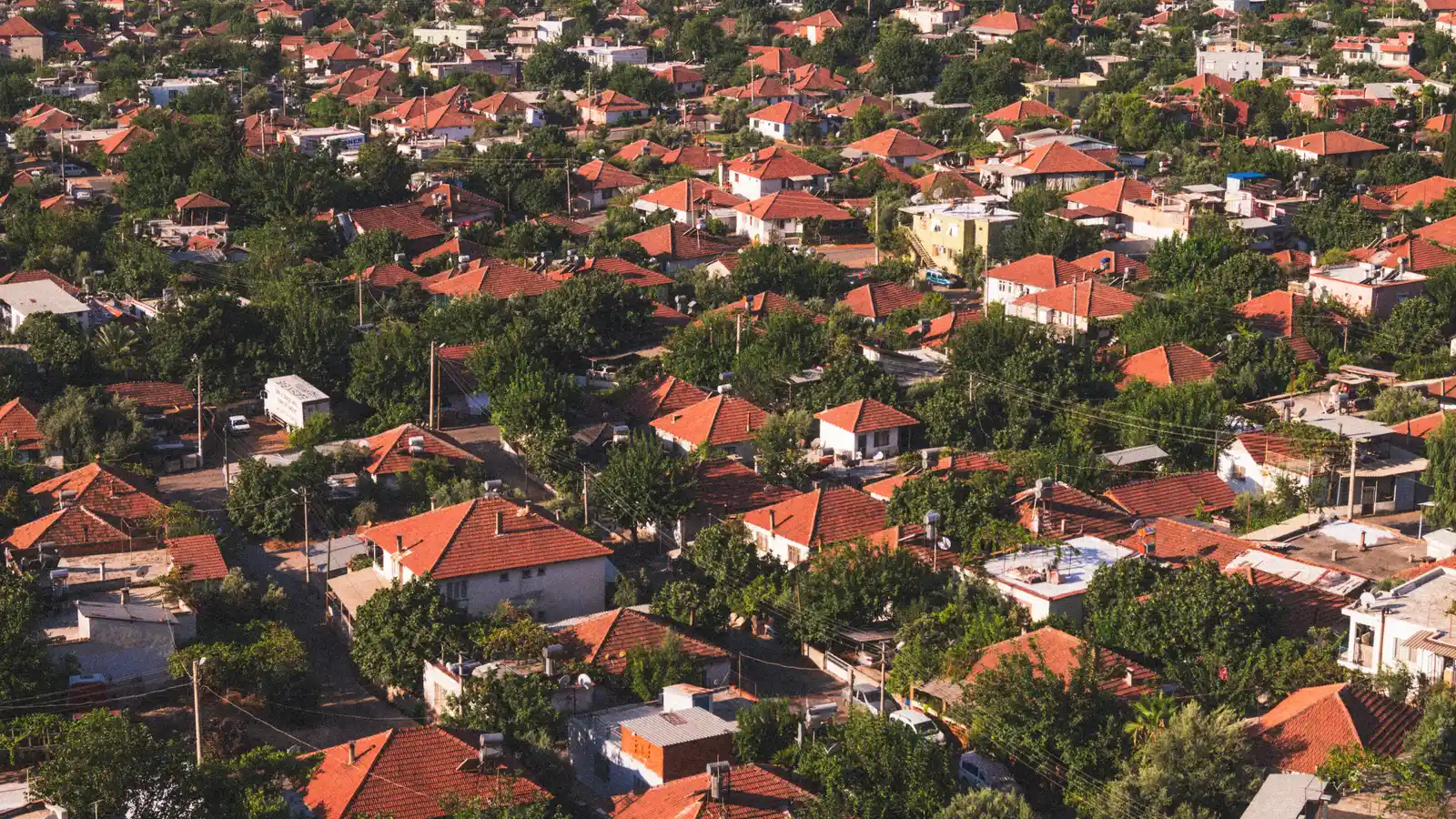 Vibrant aerial view of a suburban neighborhood with red-tiled roofs surrounded by lush greenery.