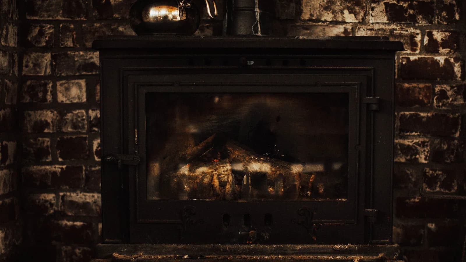 A warm and inviting vintage fireplace against a rustic brick wall, perfect for cozy winter settings.