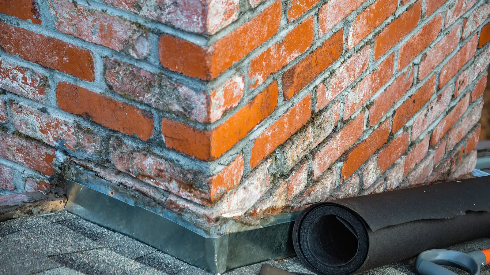 Detailed view of a brick chimney featuring construction tools and materials for repair.