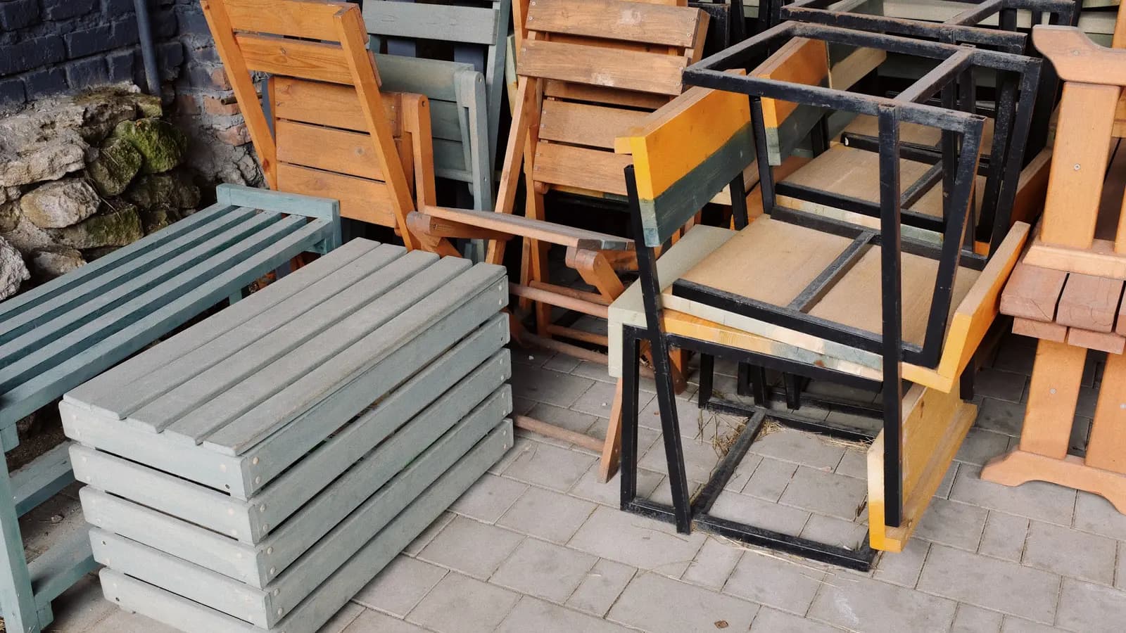 Outdoor chairs and tables with wood, painted slats, and metal frames arranged on a paved patio