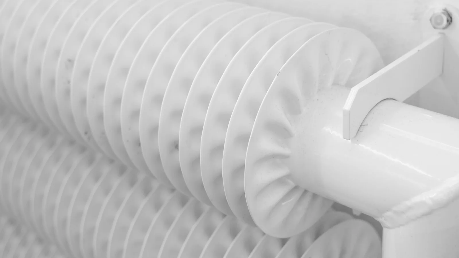 Finned hydronic baseboard heater mounted low along a wall with its heating element visible