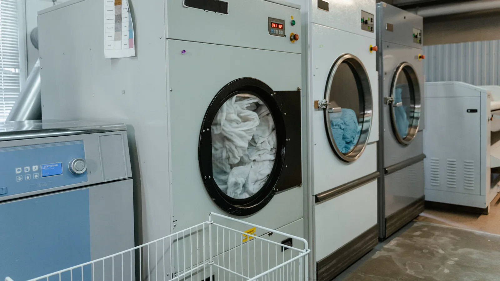 Interior view of industrial laundry machines in a facility with linens being washed.