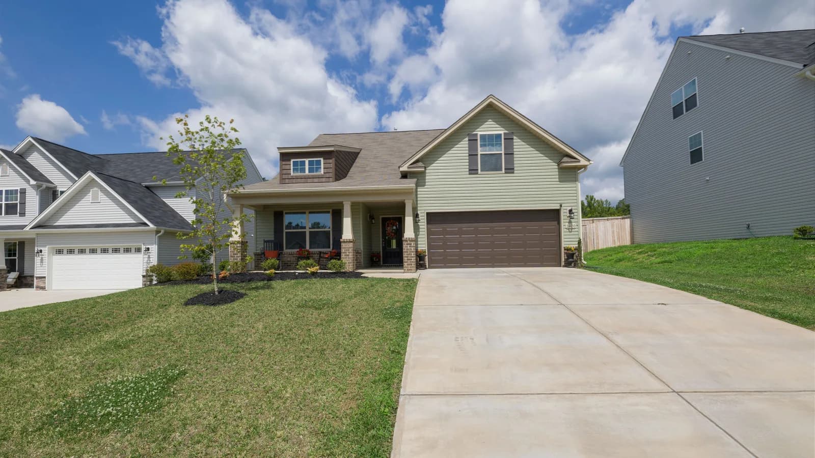 A modern suburban detached house with a spacious driveway under a bright blue sky.