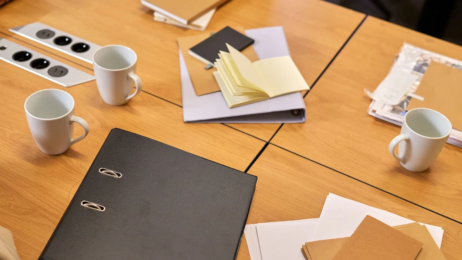 A neat office desk with binders, papers, and coffee mugs arranged neatly, offering a professional workspace vibe.