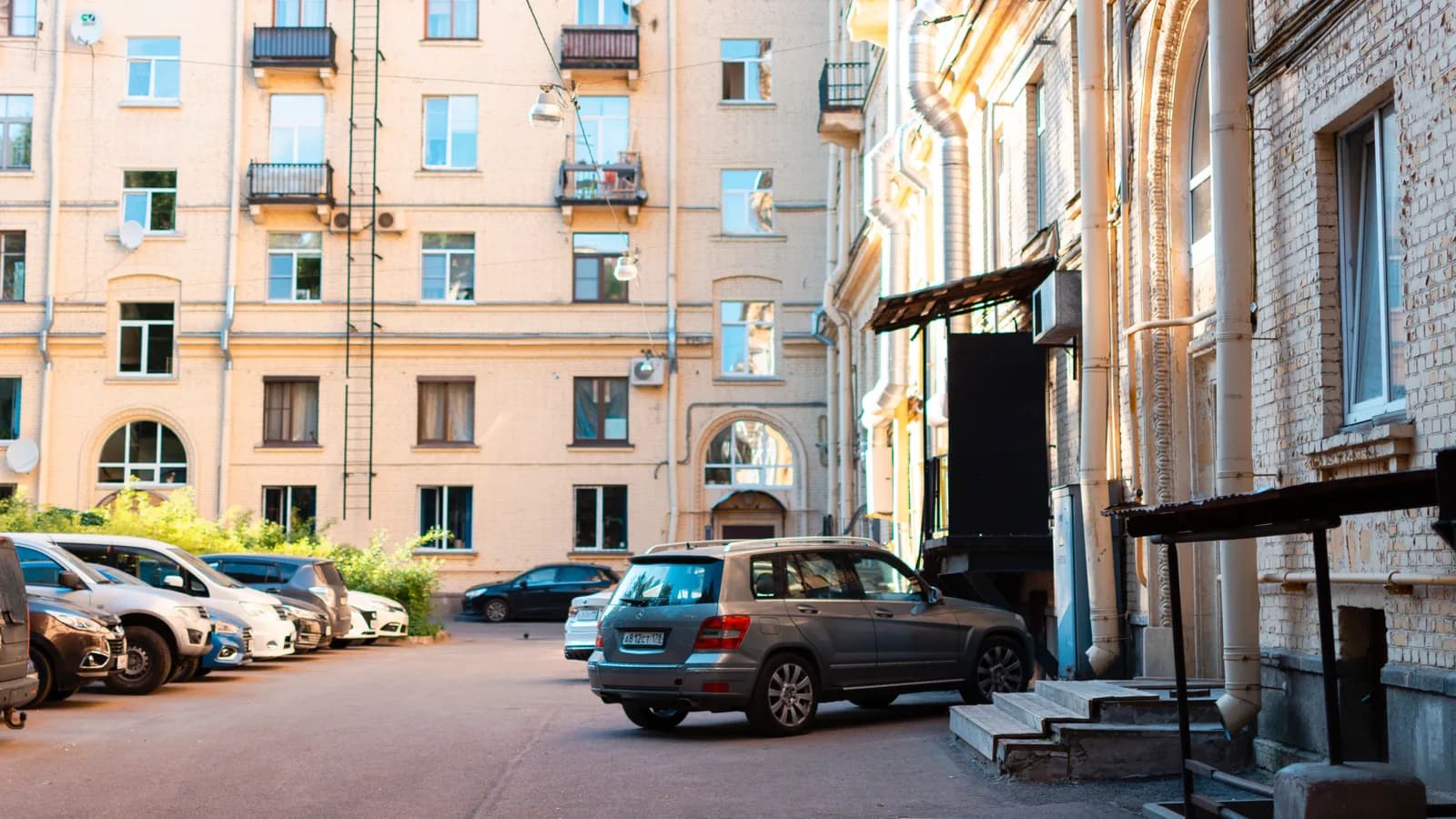 A bright urban courtyard with parked cars and classic apartment buildings in daylight.