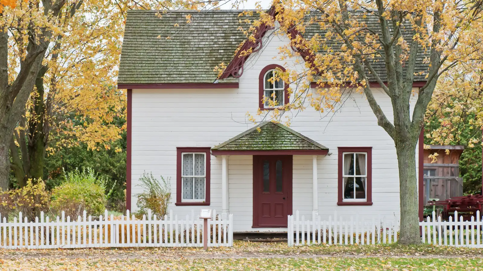 Picturesque traditional house with autumn foliage and a white picket fence in London, Ontario.