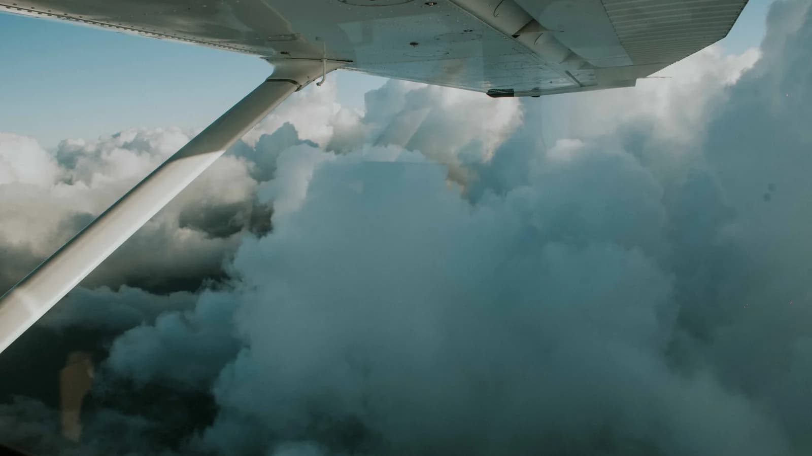 A serene view of dense clouds from an airplane wing, capturing the essence of flight and exploration.