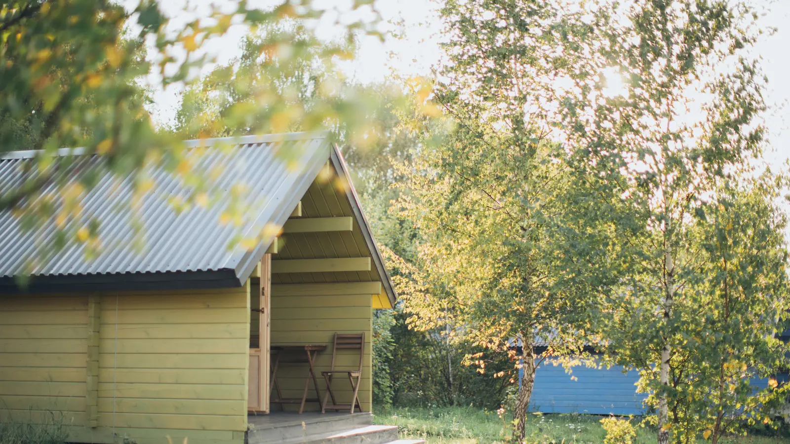 A serene wooden cabin surrounded by trees in a sunlit forest setting.