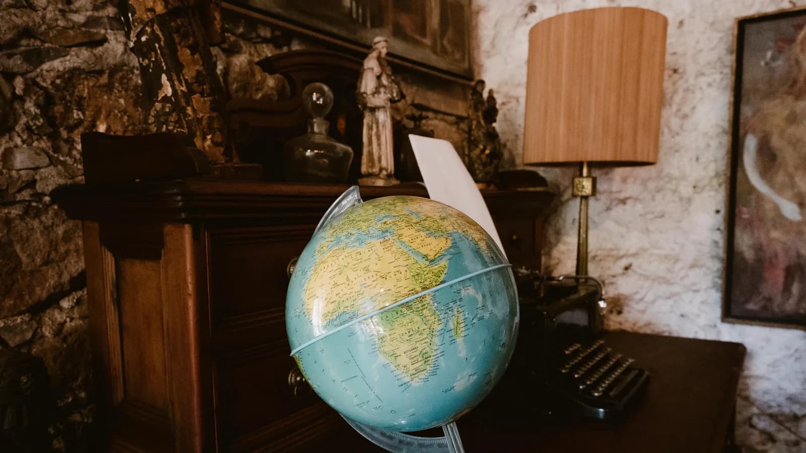 A vintage-style desktop featuring a globe and classic typewriter on a wooden desk.