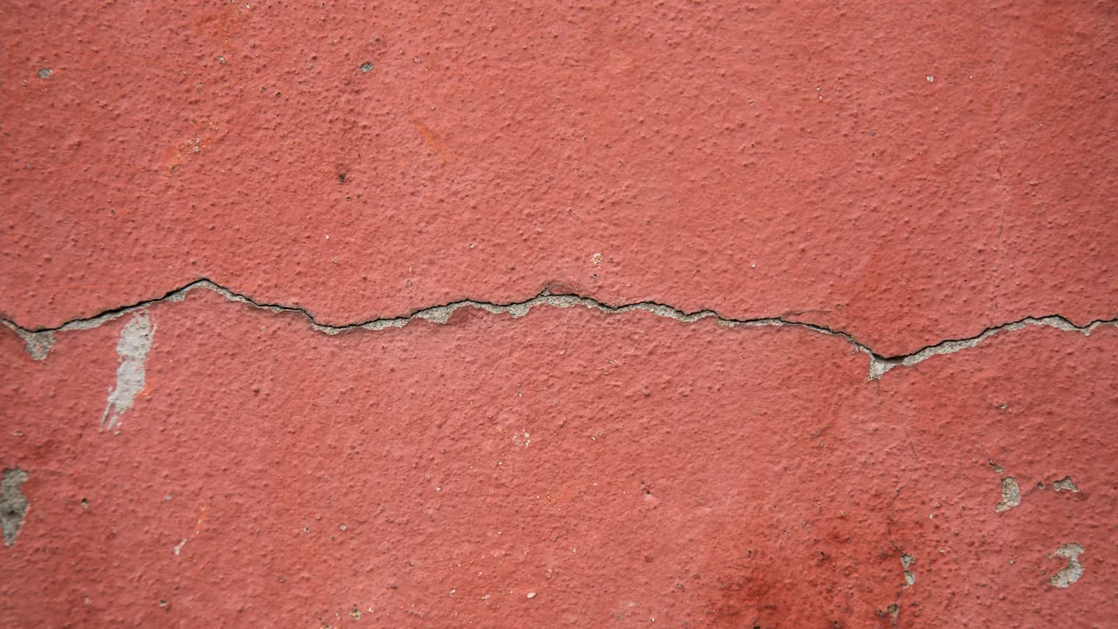 High-resolution image of a cracked red-painted concrete wall surface for texture background.