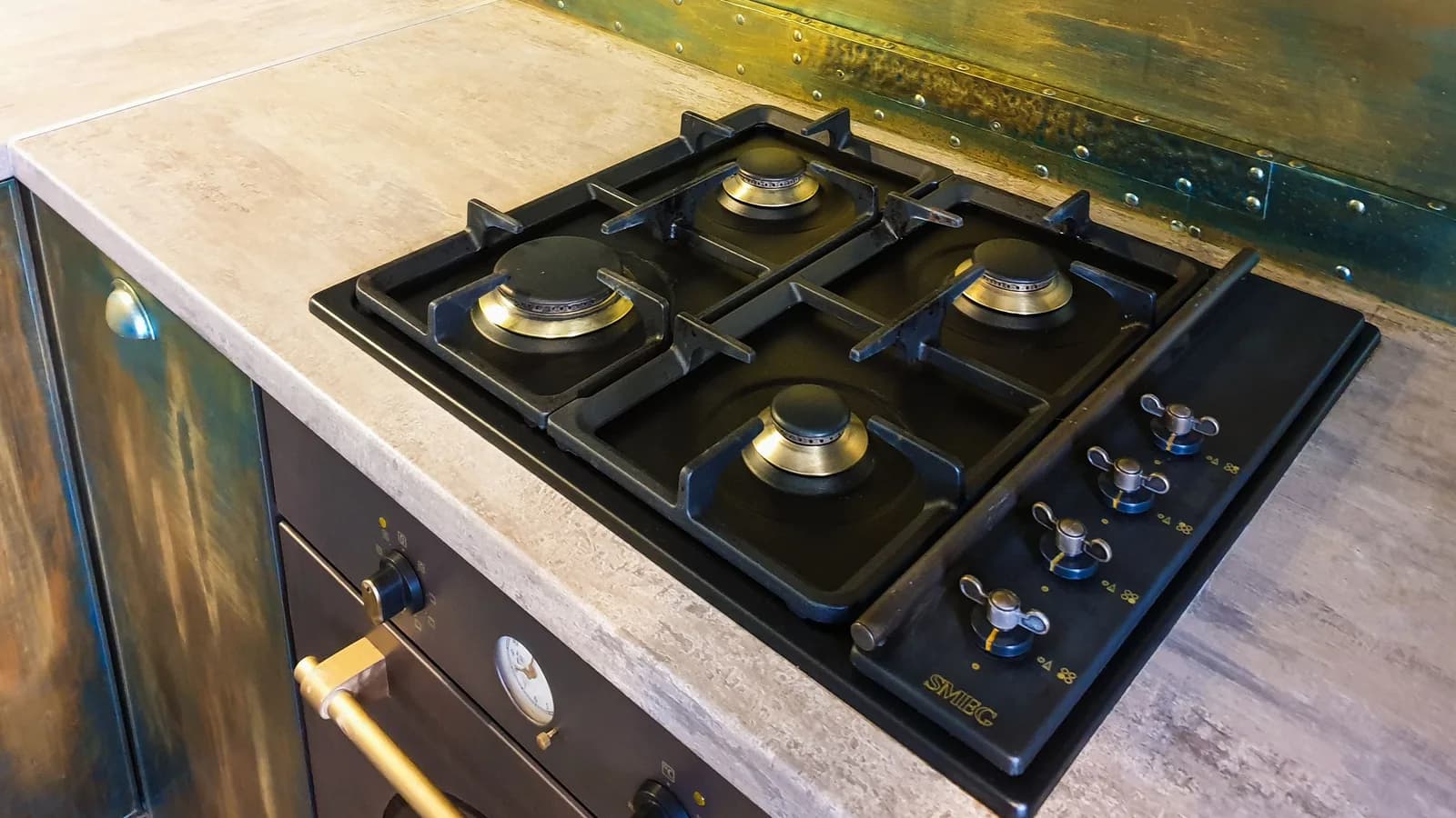 Close-up of a sleek modern gas stove on a rustic industrial style kitchen counter.