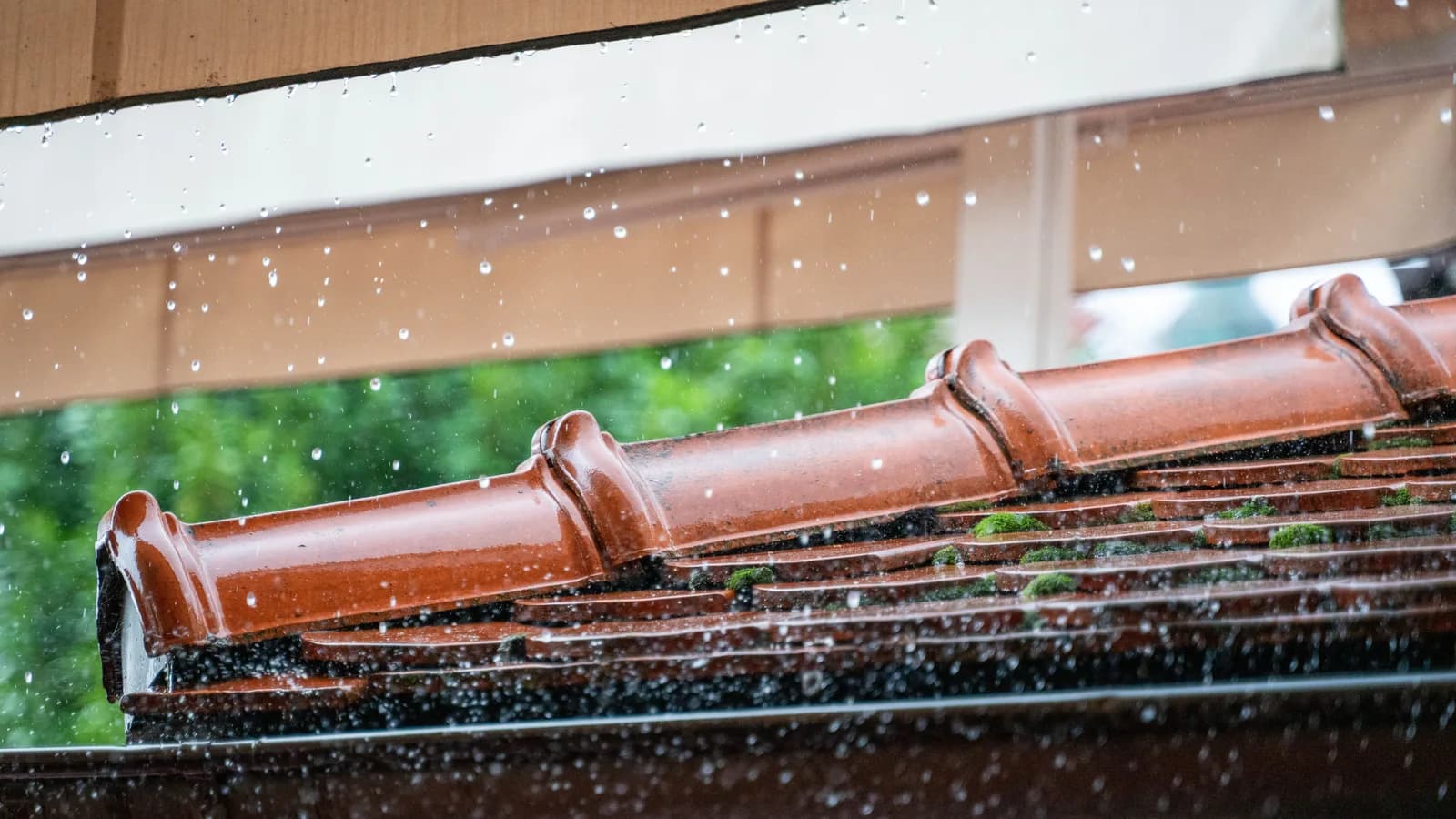 Detailed view of rain droplets cascading off a terracotta roof, capturing the essence of a rainy day.