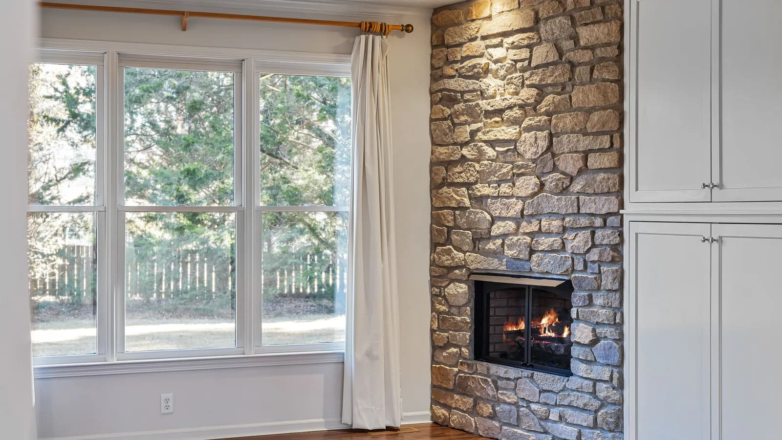 Curtain rod mounted above a wide living room window with floor-length panels