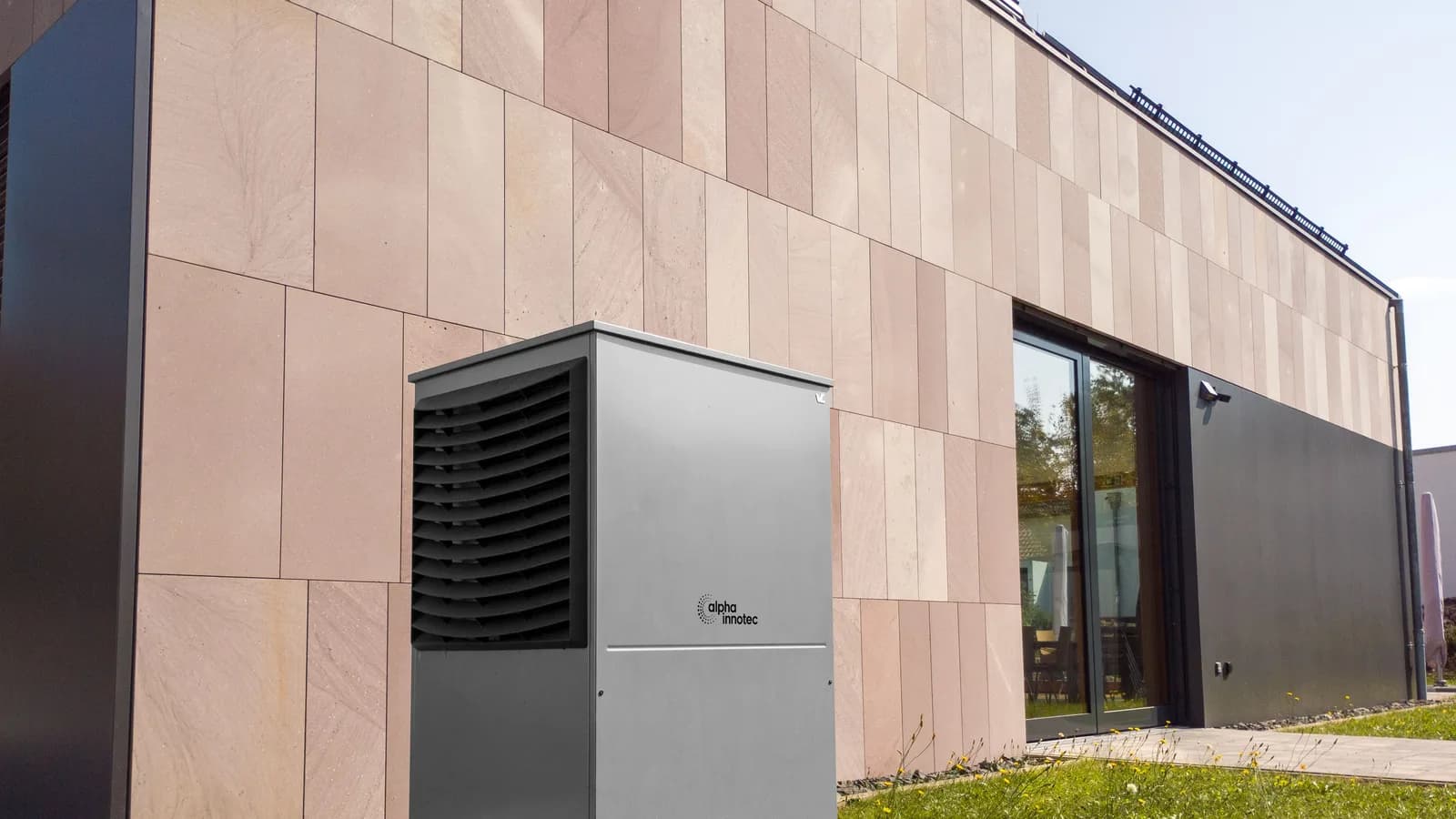 A modern heat pump unit installed outdoors next to a contemporary building, showcasing renewable energy technology.