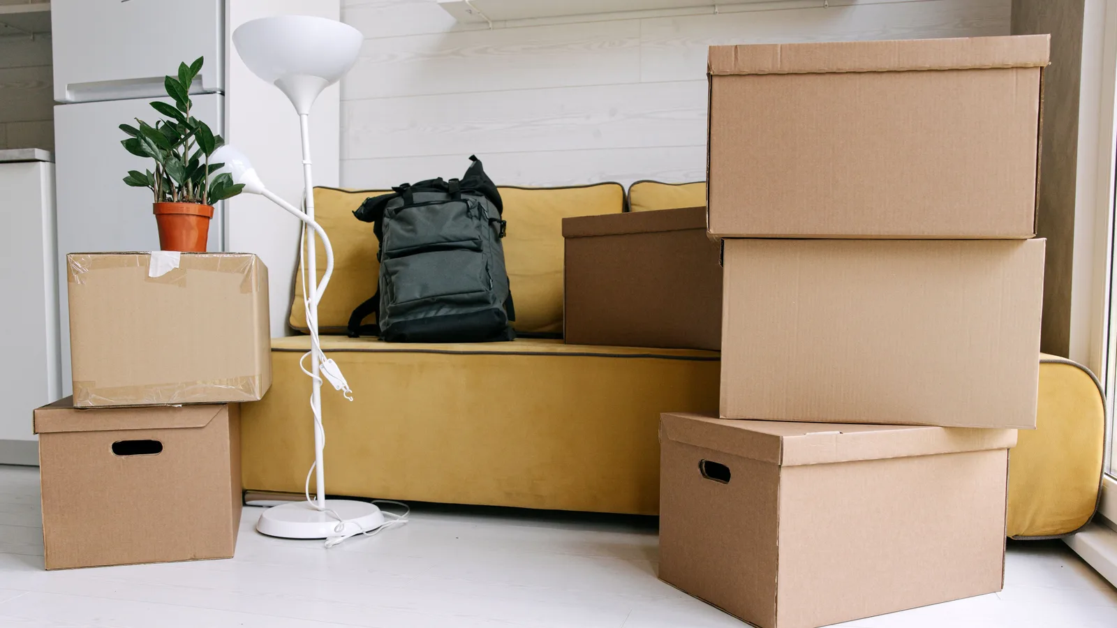 Cardboard boxes and a backpack in a cozy living room signify moving day excitement.