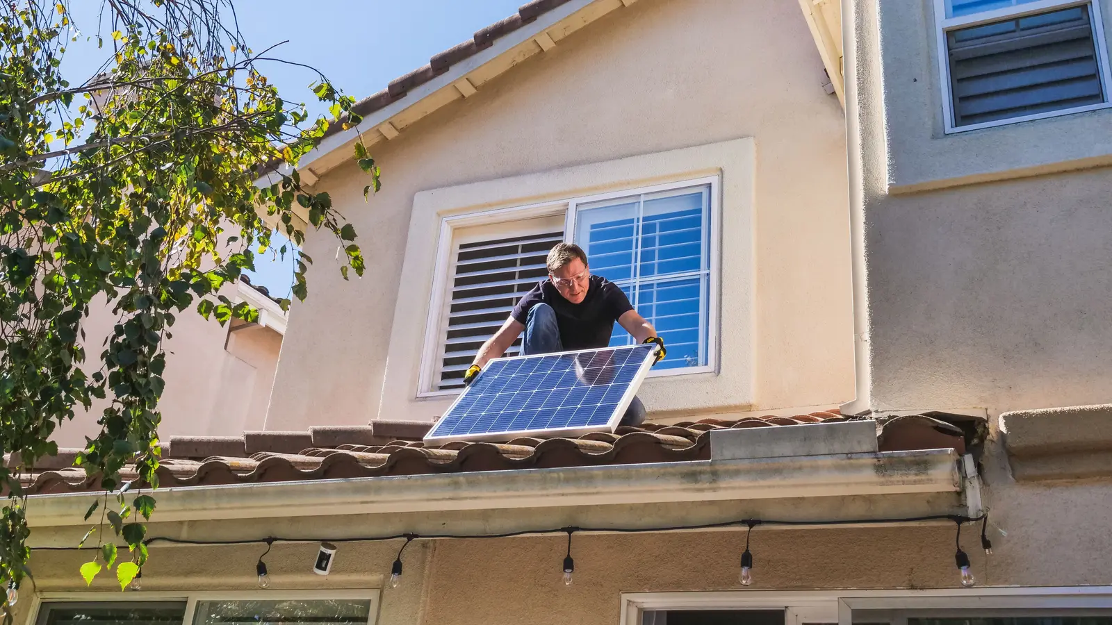 Solar technician installing photovoltaic panels on a sunny rooftop.