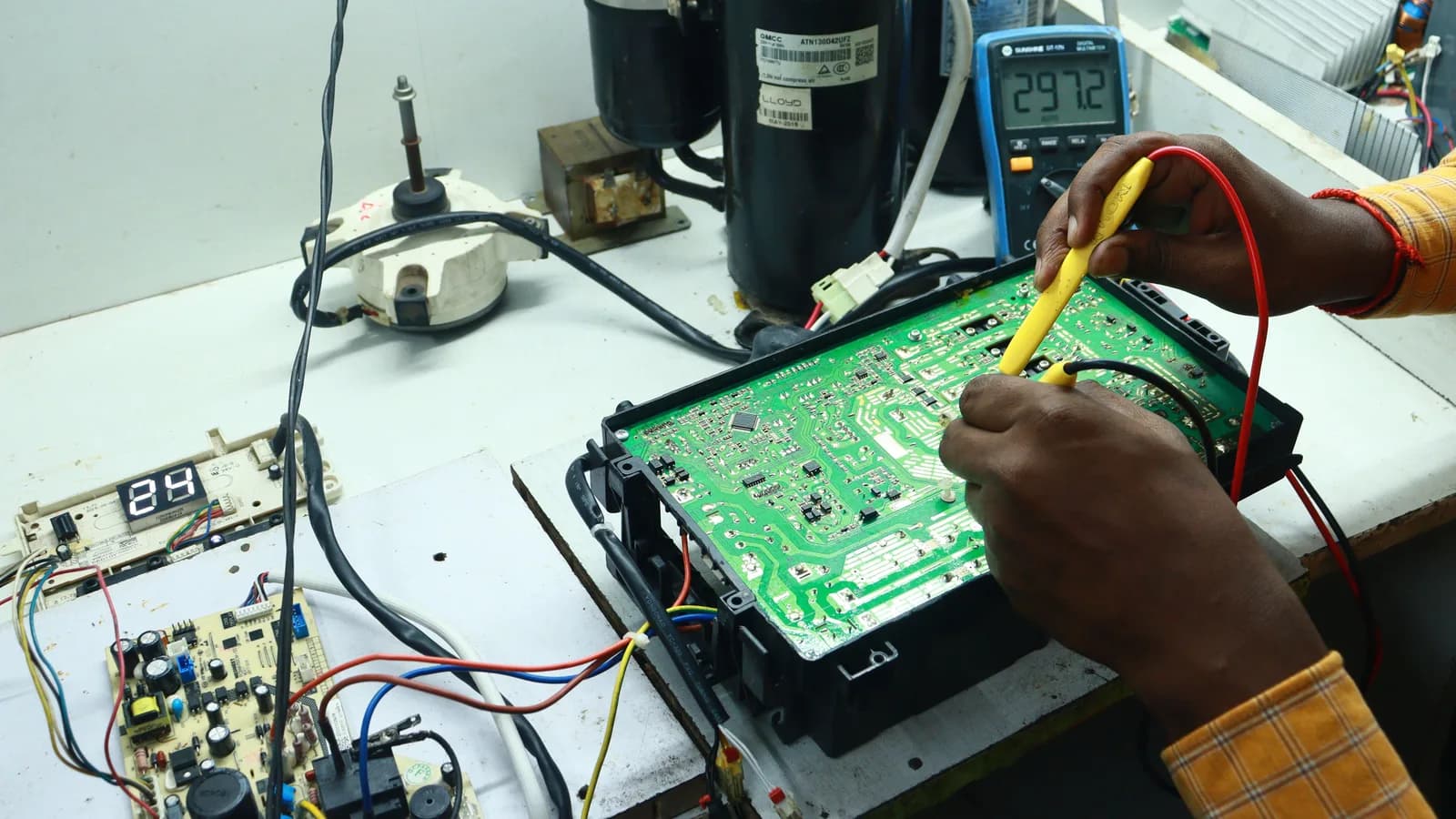 Technician working on AC PCB with tools and equipment, captured in New Delhi workshop.
