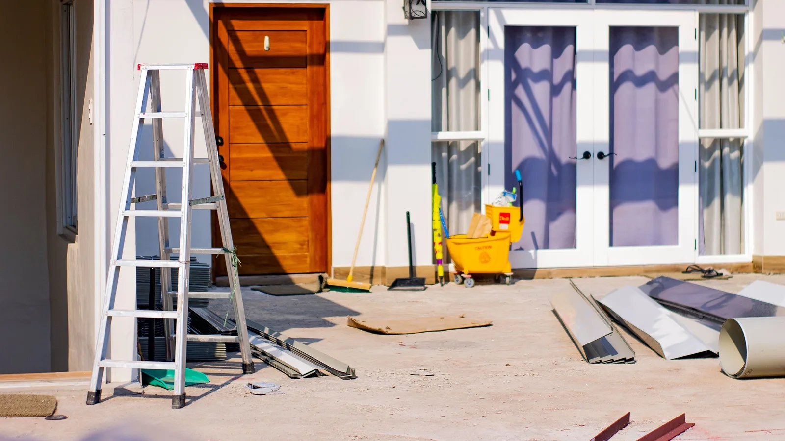 Front entrance of a house under renovation with tools and materials scattered around.