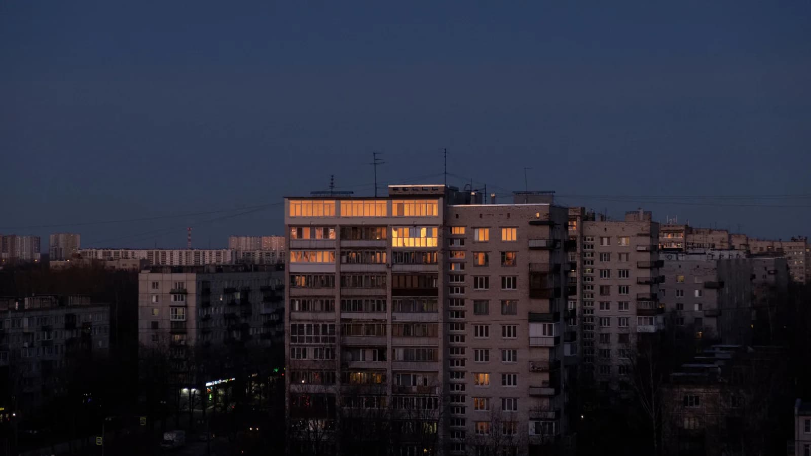 Urban buildings at dusk with illuminated windows, capturing a serene cityscape moment.