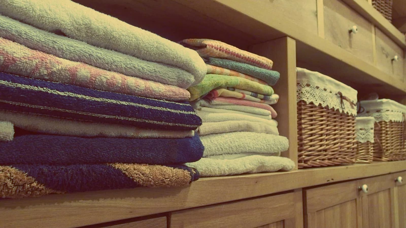 A linen cabinet with folded towels arranged beside woven storage baskets