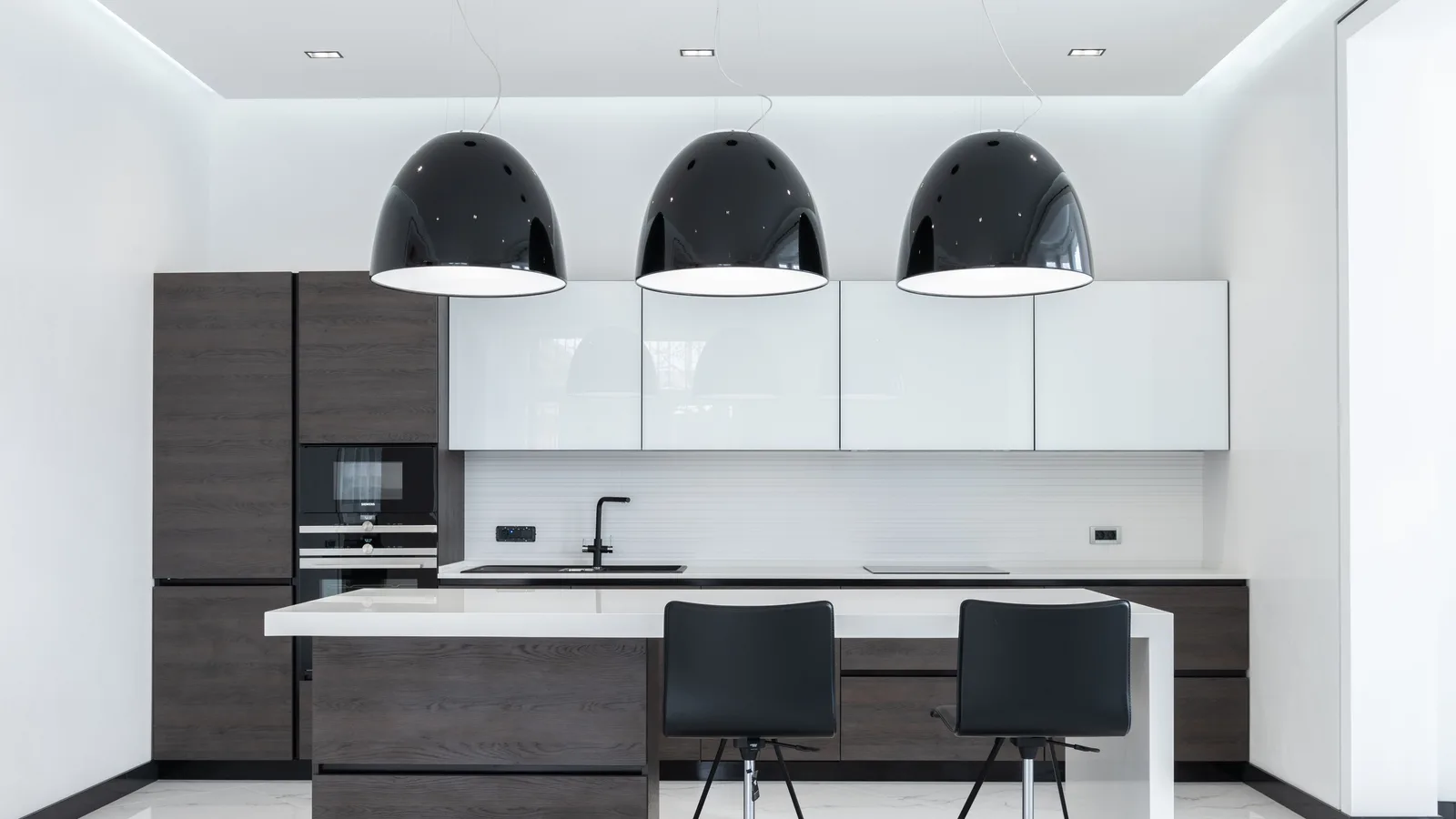 Creative lamps hanging over table with chairs in spacious kitchen with modern furniture and appliances