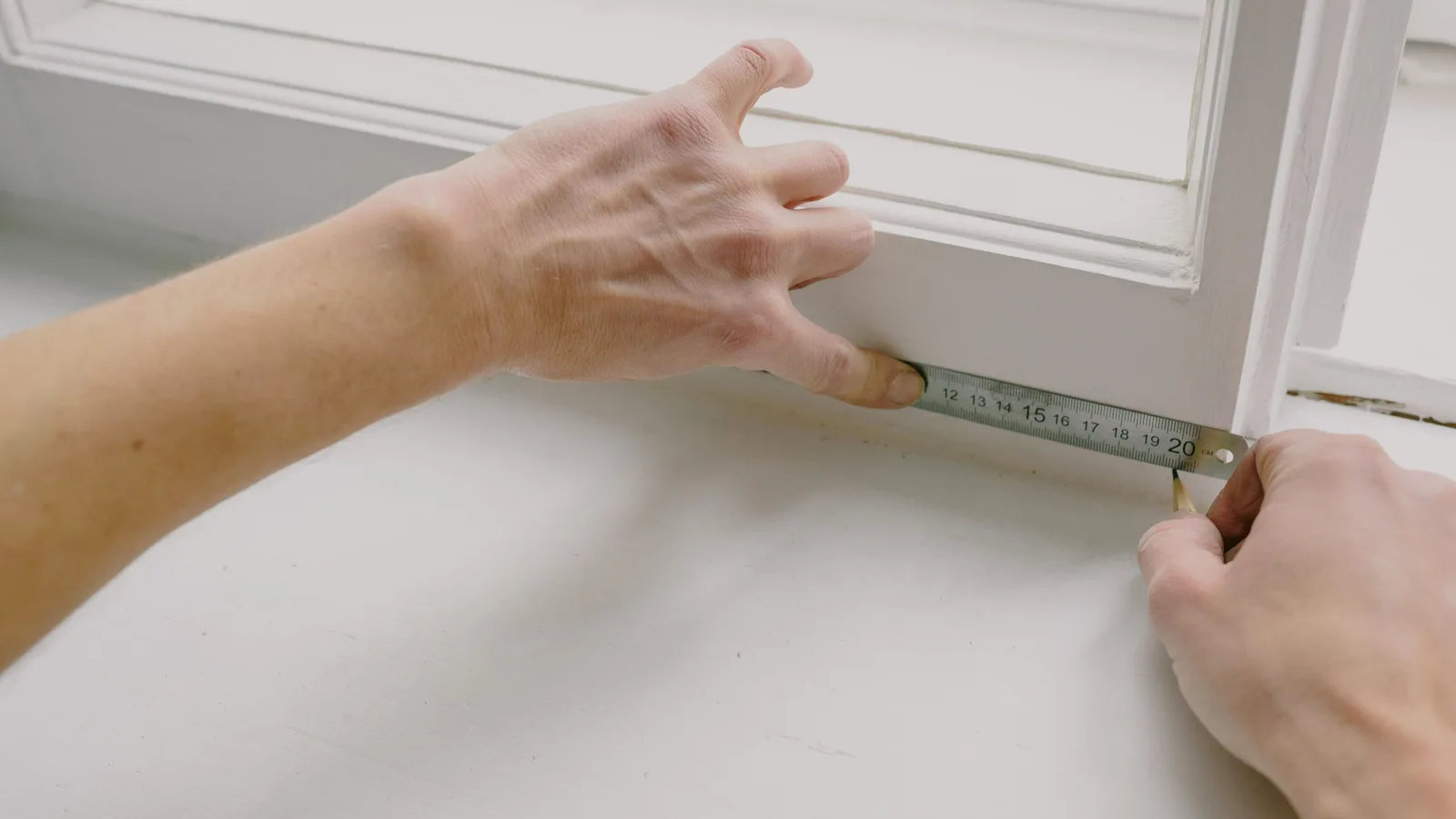 Steel tape measure spanning the inside width of a bright window opening before cordless blinds are ordered
