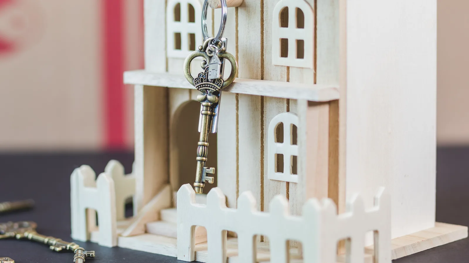Miniature wooden house with a vintage key, symbolizing real estate and homeownership.