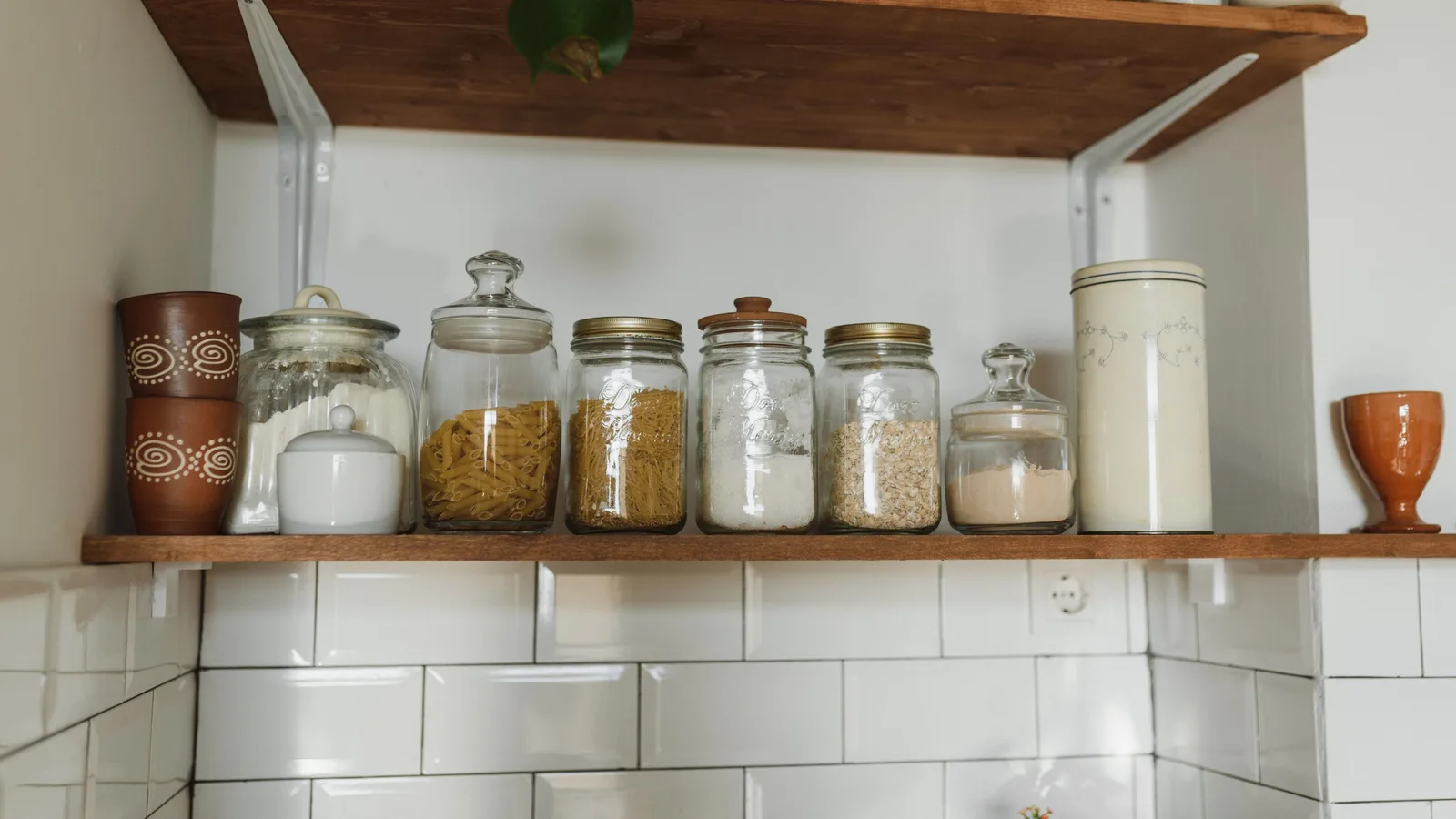 Aesthetic kitchen shelves displaying various jars and containers for organized storage.