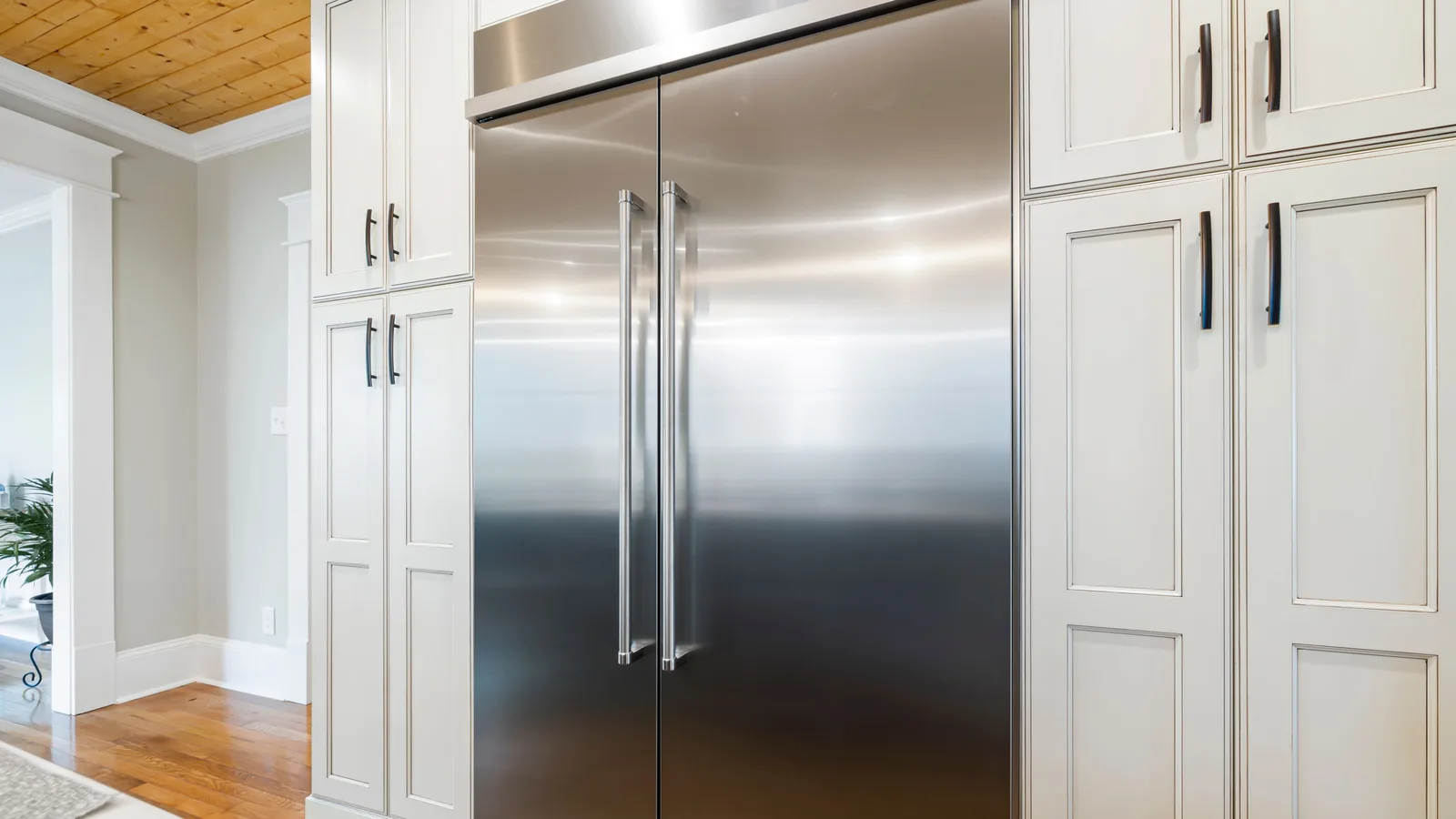 Sleek stainless steel refrigerator amidst elegant cabinetry in a bright kitchen.