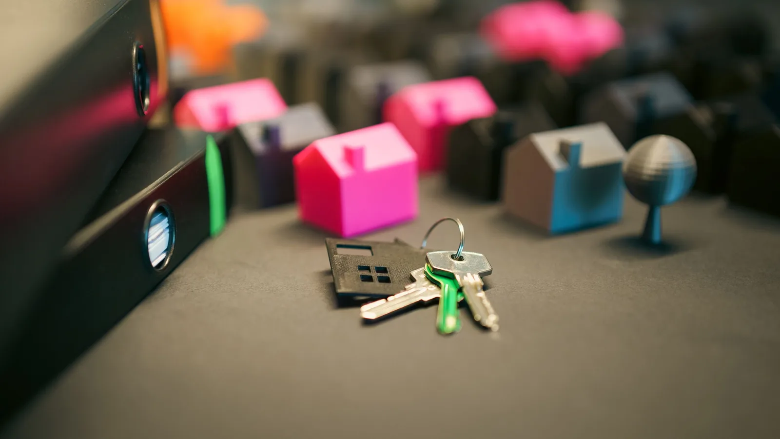 Miniature model houses and keys on a desk, symbolizing real estate and property investment.
