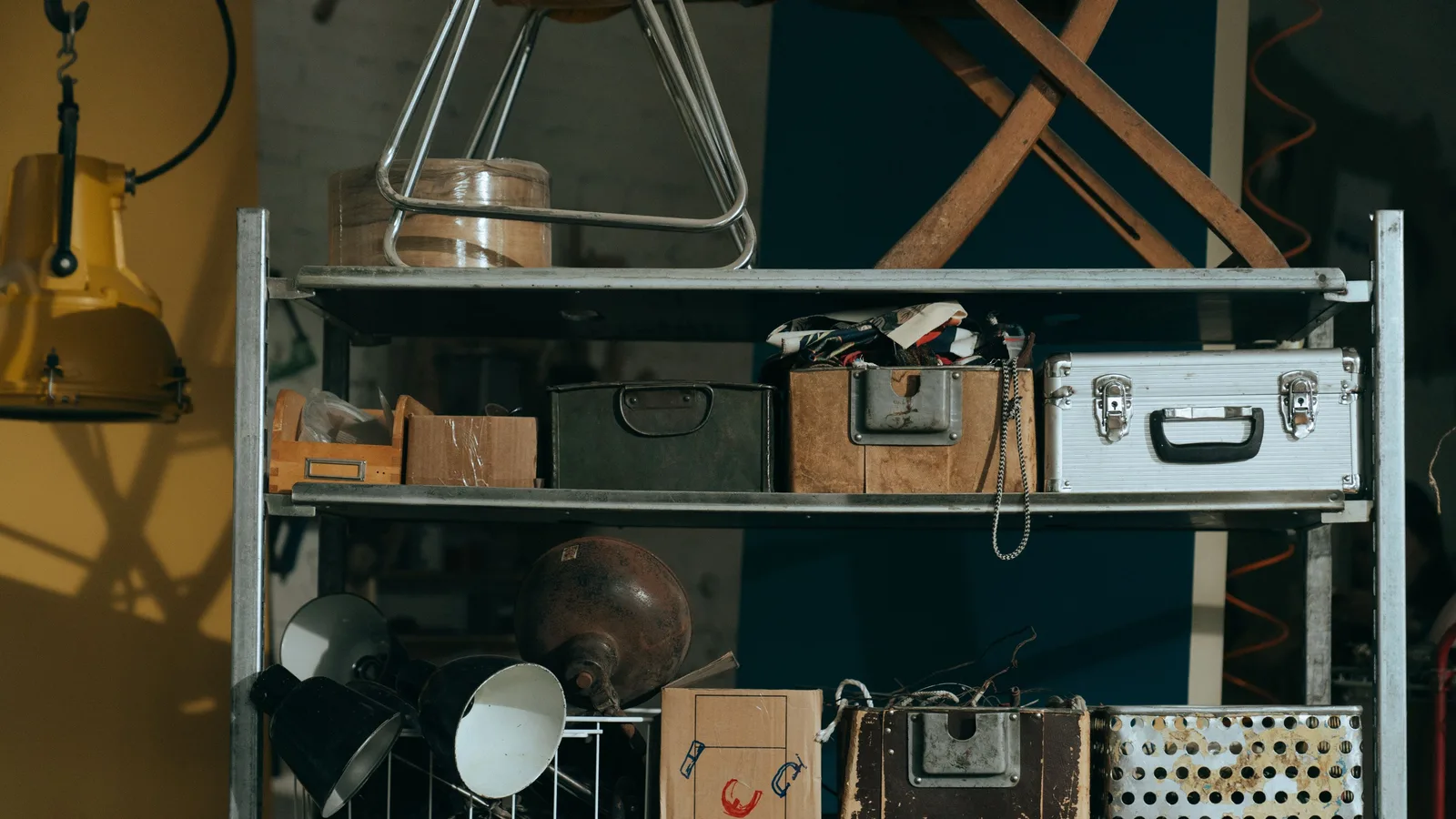 A shelf in a workshop holding vintage and retro objects, showcasing old storage boxes and tools.