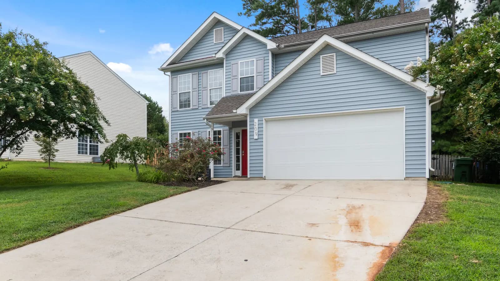Closed white sectional garage door meeting a concrete driveway at the bottom edge