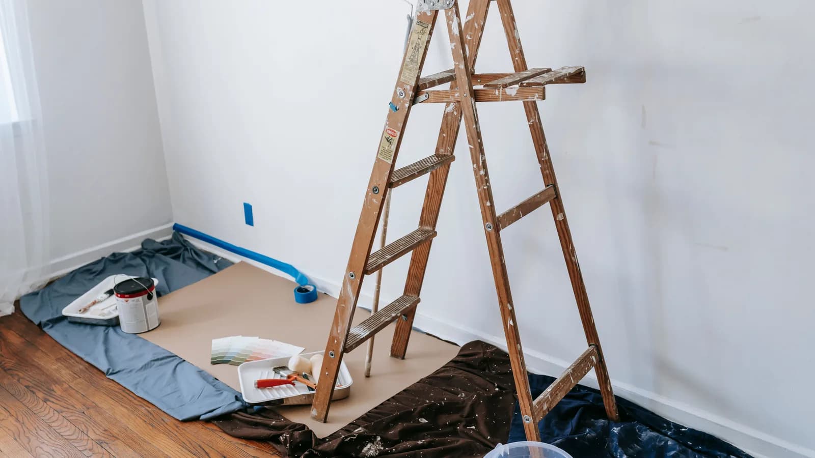 A room under renovation with a wooden ladder and paint materials, ready for a makeover.