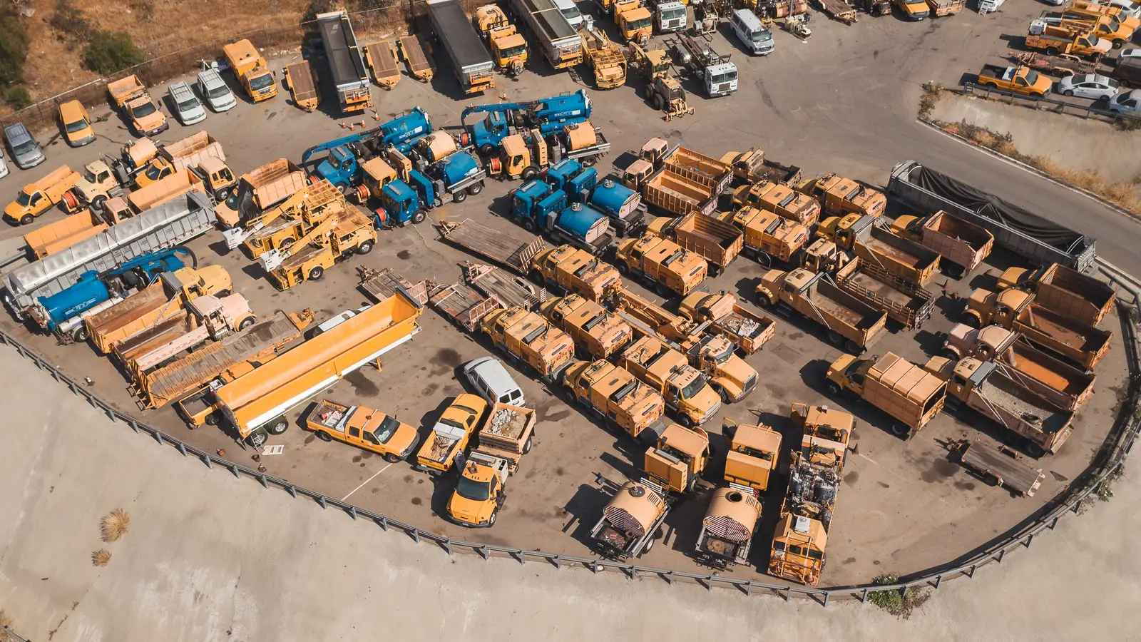 Drone shot of a parking lot filled with industrial vehicles, showcasing an organized layout from above.