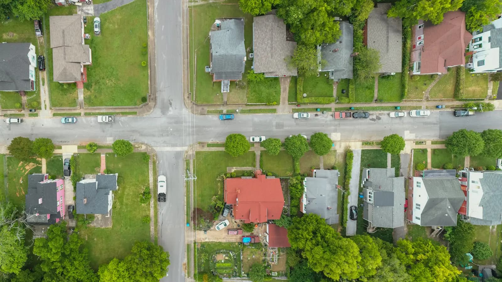 Aerial photo capturing an intersection in a suburban neighborhood with houses and greenery.
