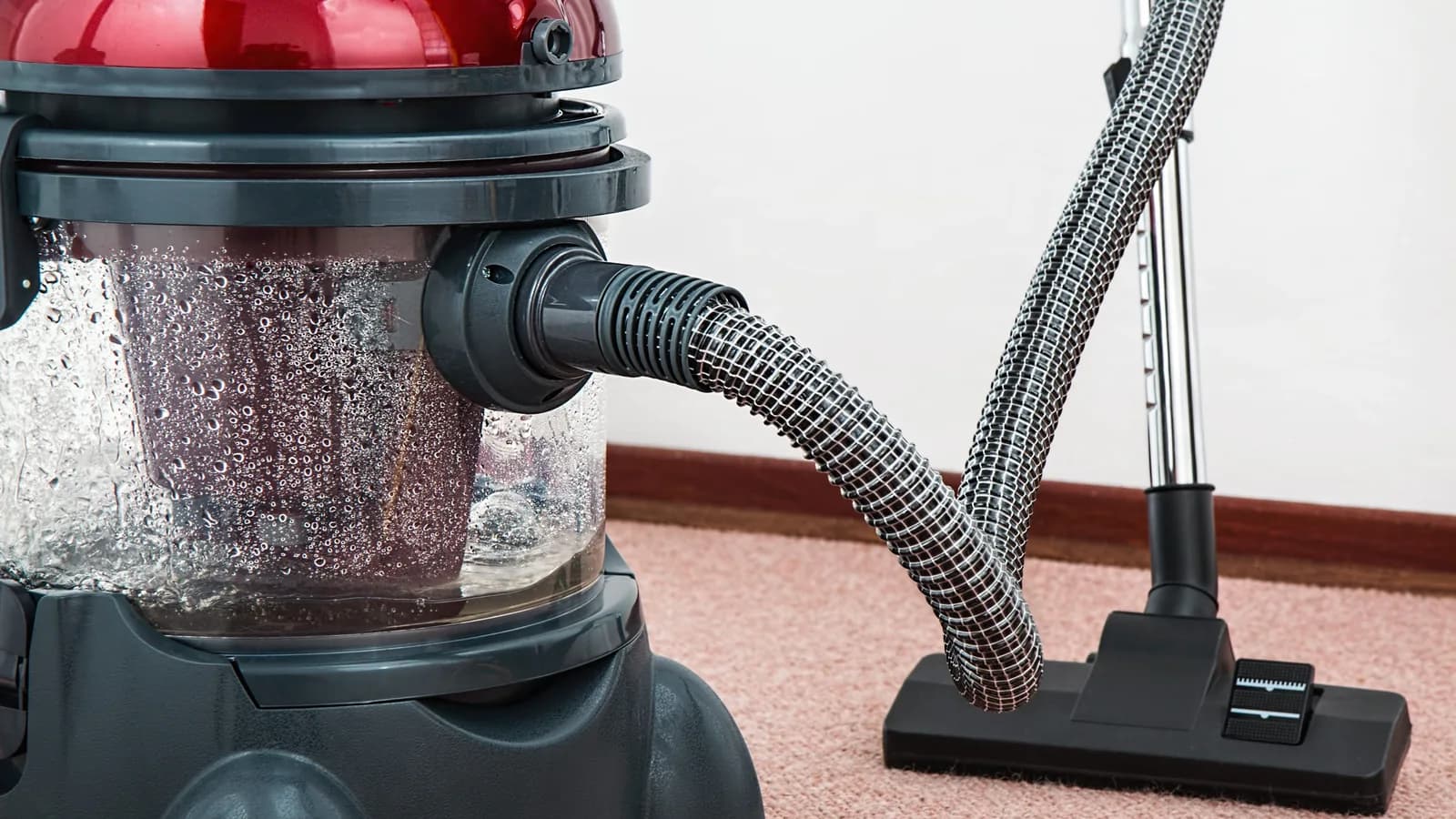 Close-up of a modern vacuum cleaner with water filtration on carpet floor indoors.