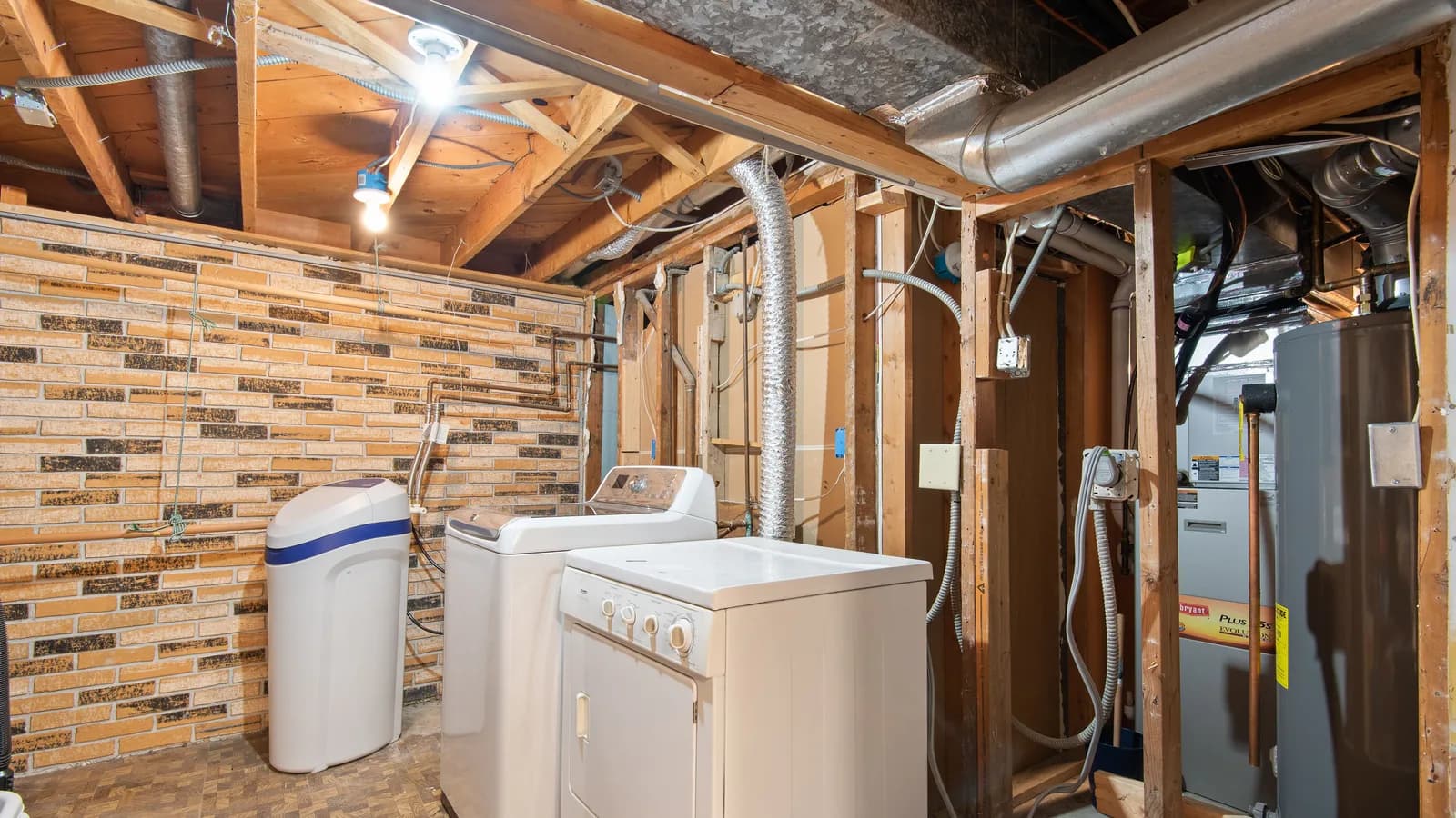 Spacious basement laundry room featuring modern appliances and exposed brickwork.