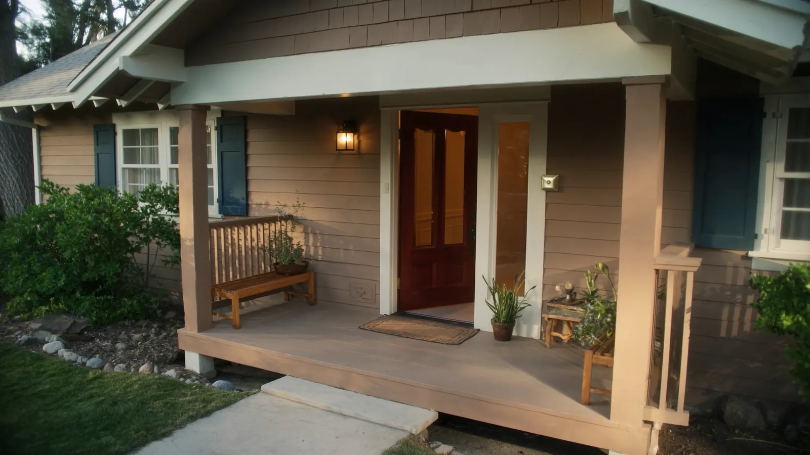 Craftsman-style house front porch with the door open and warm light glowing from inside at golden hour