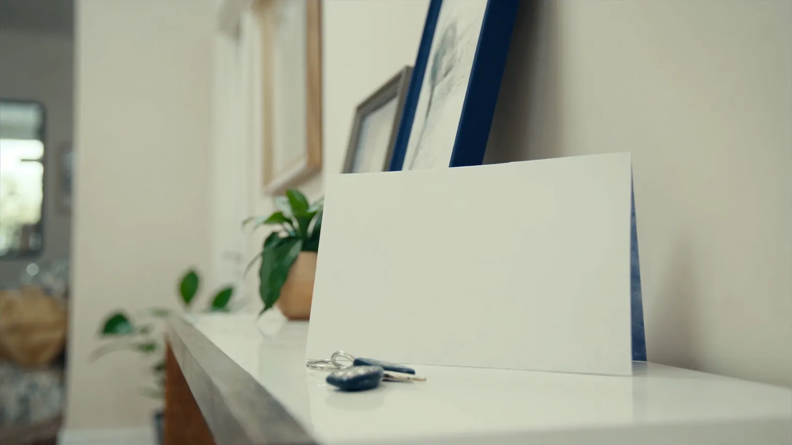 Minimalist flat-lay of house keys, a closed blank notebook, and a warm ceramic mug on a clean wooden desk in soft window light