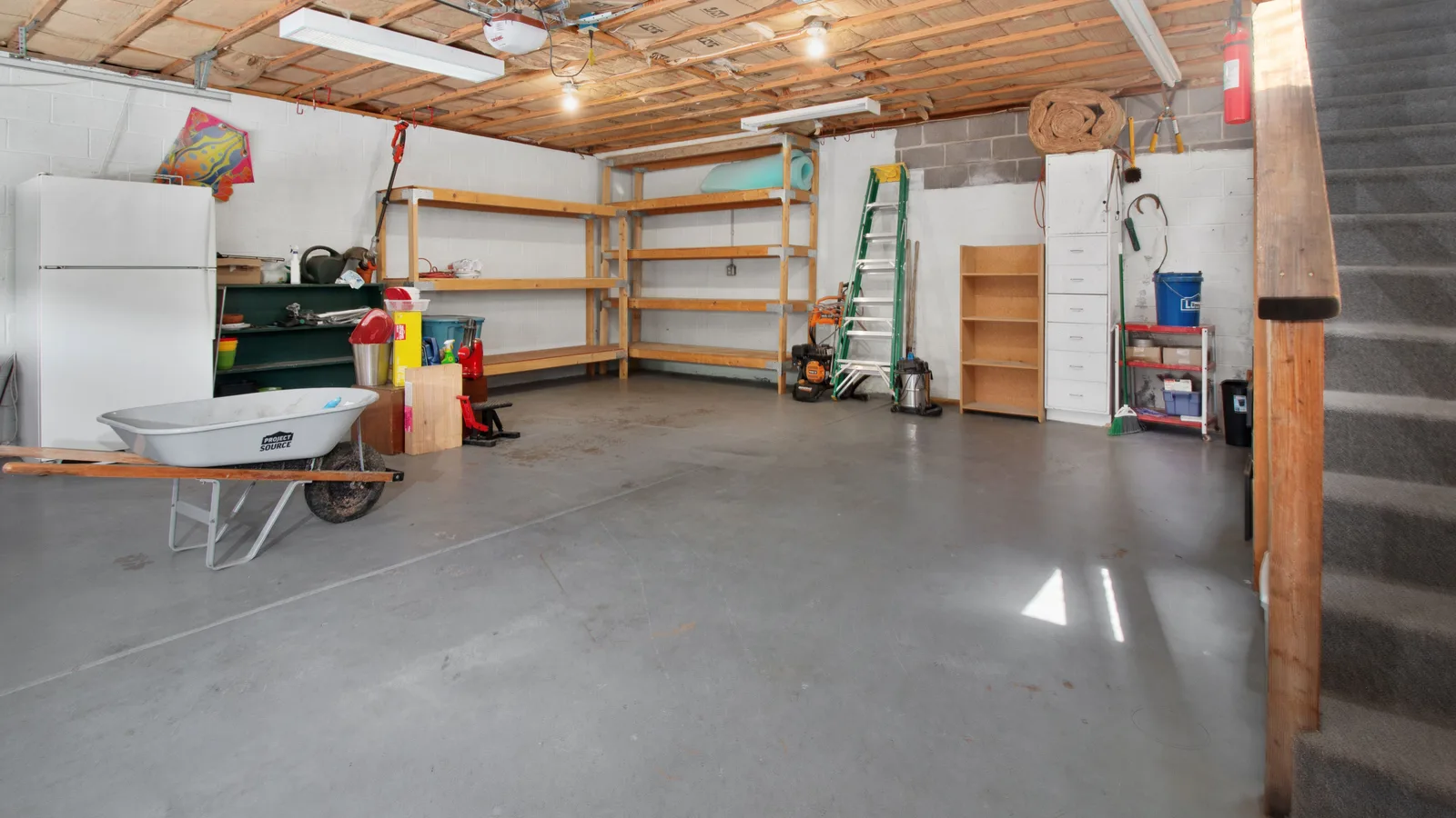 A full-size refrigerator standing in an organized residential garage beside storage shelves