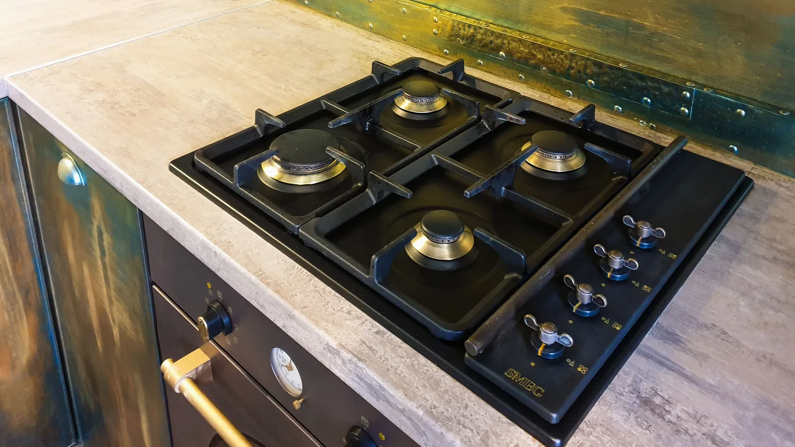 Close-up of a sleek modern gas stove on a rustic industrial style kitchen counter.